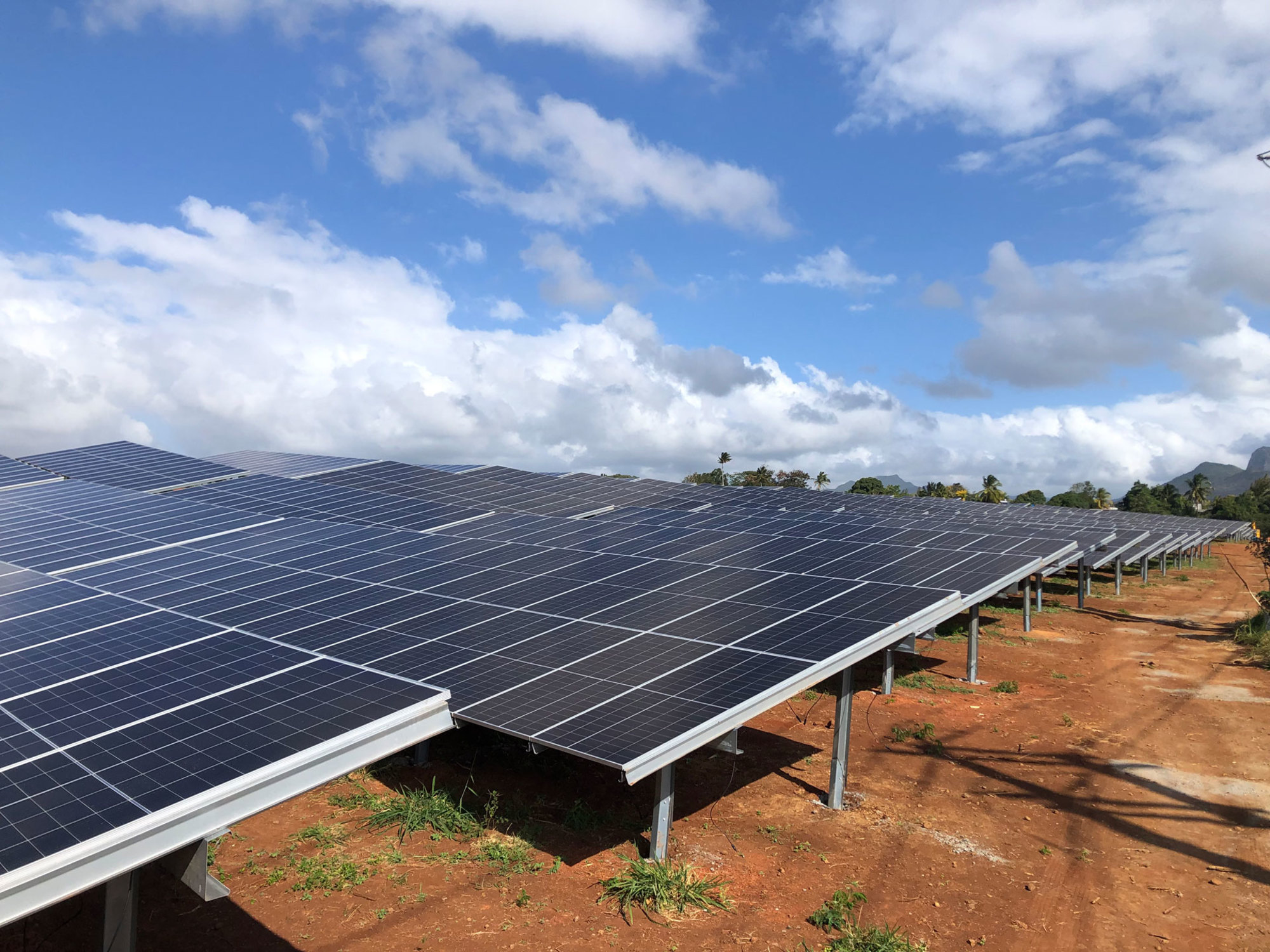 aste champ solaire avec des rangées de panneaux photovoltaïques sur structures métalliques, réalisé par Le Triangle, intégré dans un paysage agricole.